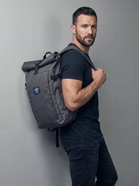Grey roll-top backpack carried on one shoulder — AI-generated product photo, same male model, frame 4 of 25