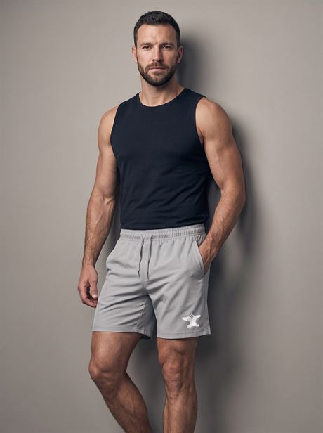 Grey sports shorts, leaning against a wall — AI-generated product photo, same male model, frame 19 of 25